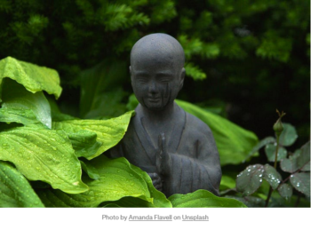 Peaceful statue among leaves in the forest.